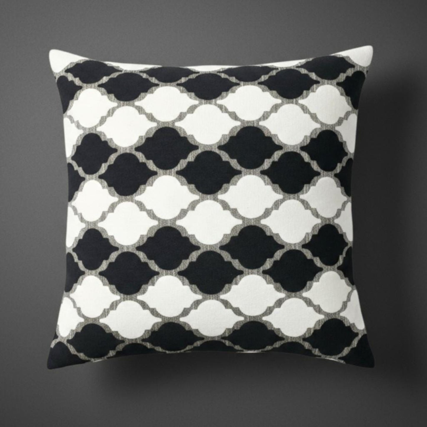 Decorative pillow with black and white geometric pattern on a dark background
