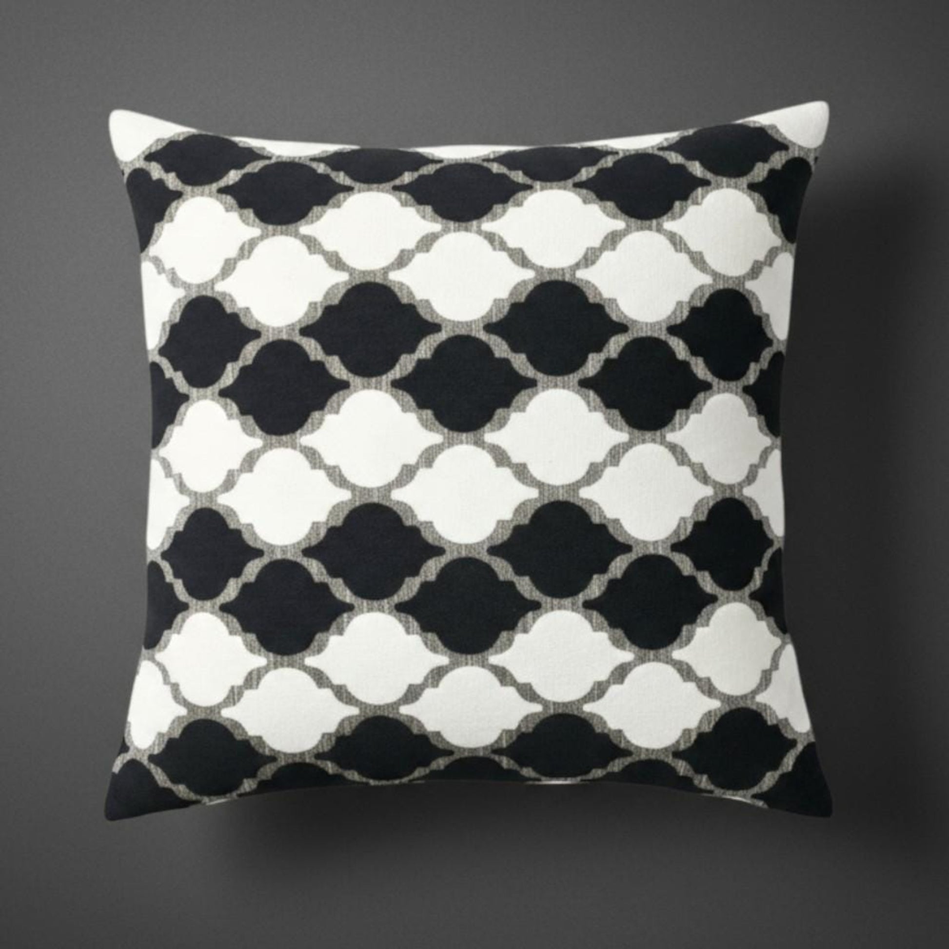 Decorative pillow with black and white geometric pattern on a dark background