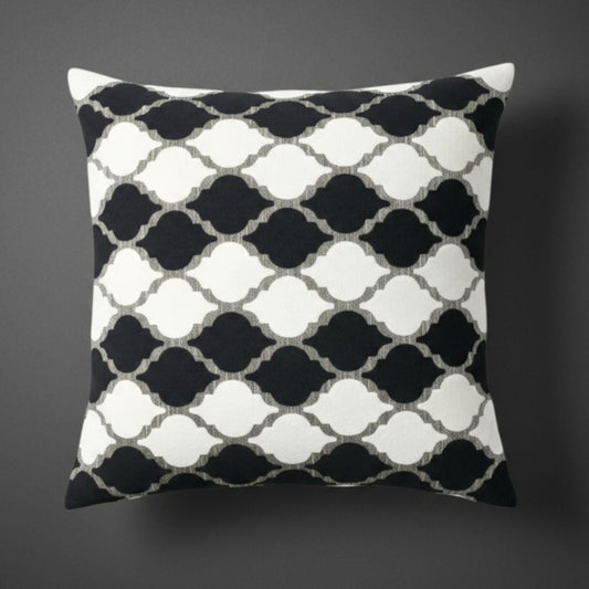Decorative pillow with black and white geometric pattern on a dark background