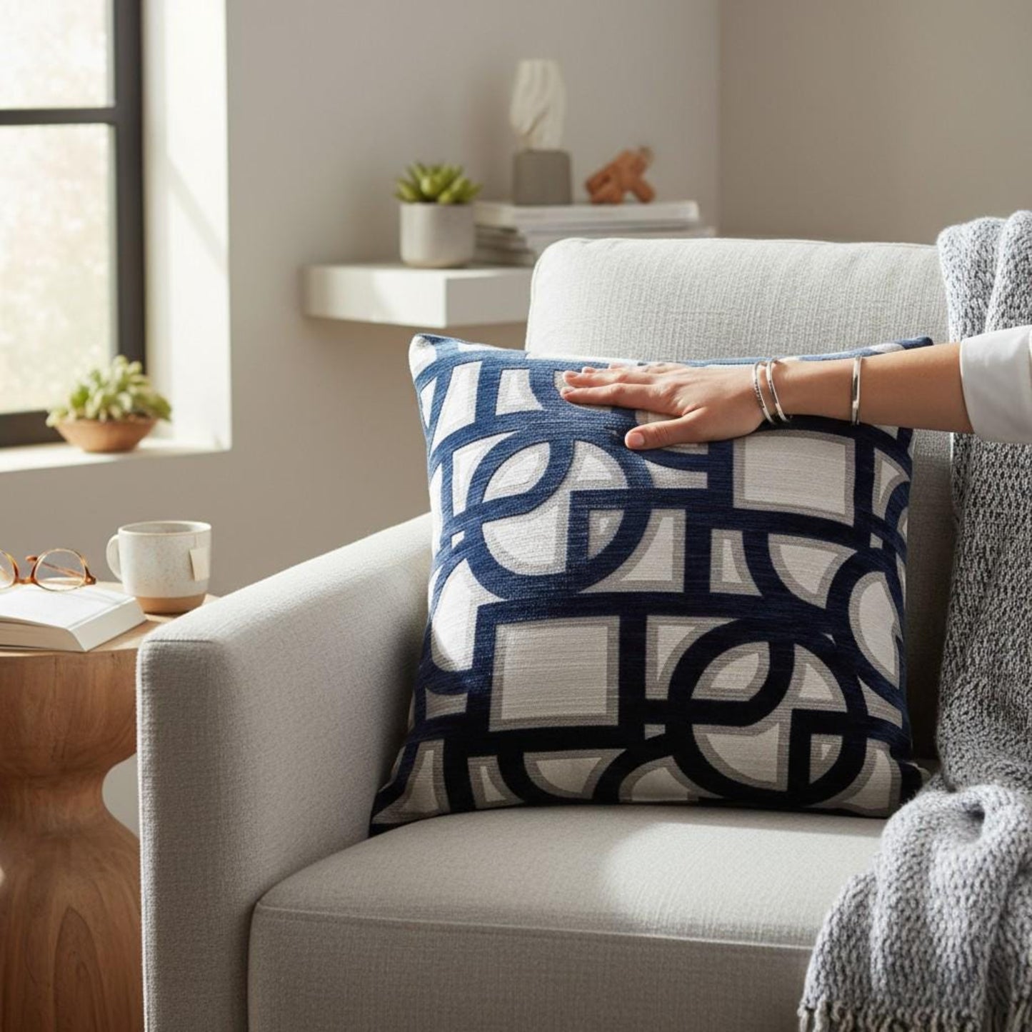 Person arranging a decorative pillow on a couch in a cozy living room.