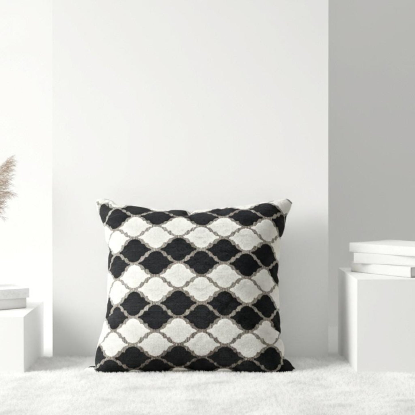 Black and white patterned pillow on a white surface with a light gray wall background