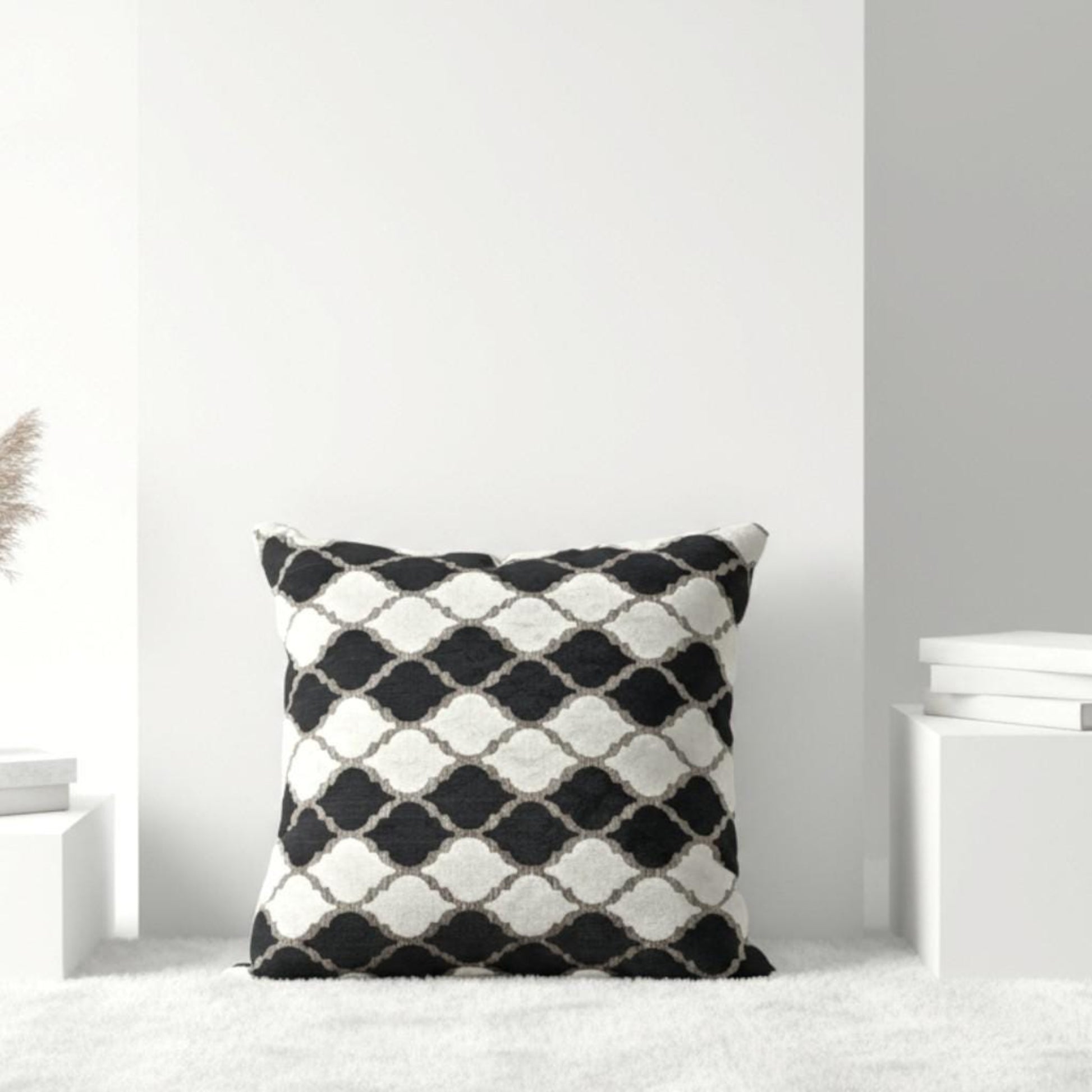 Black and white patterned pillow on a white surface with a light gray wall background