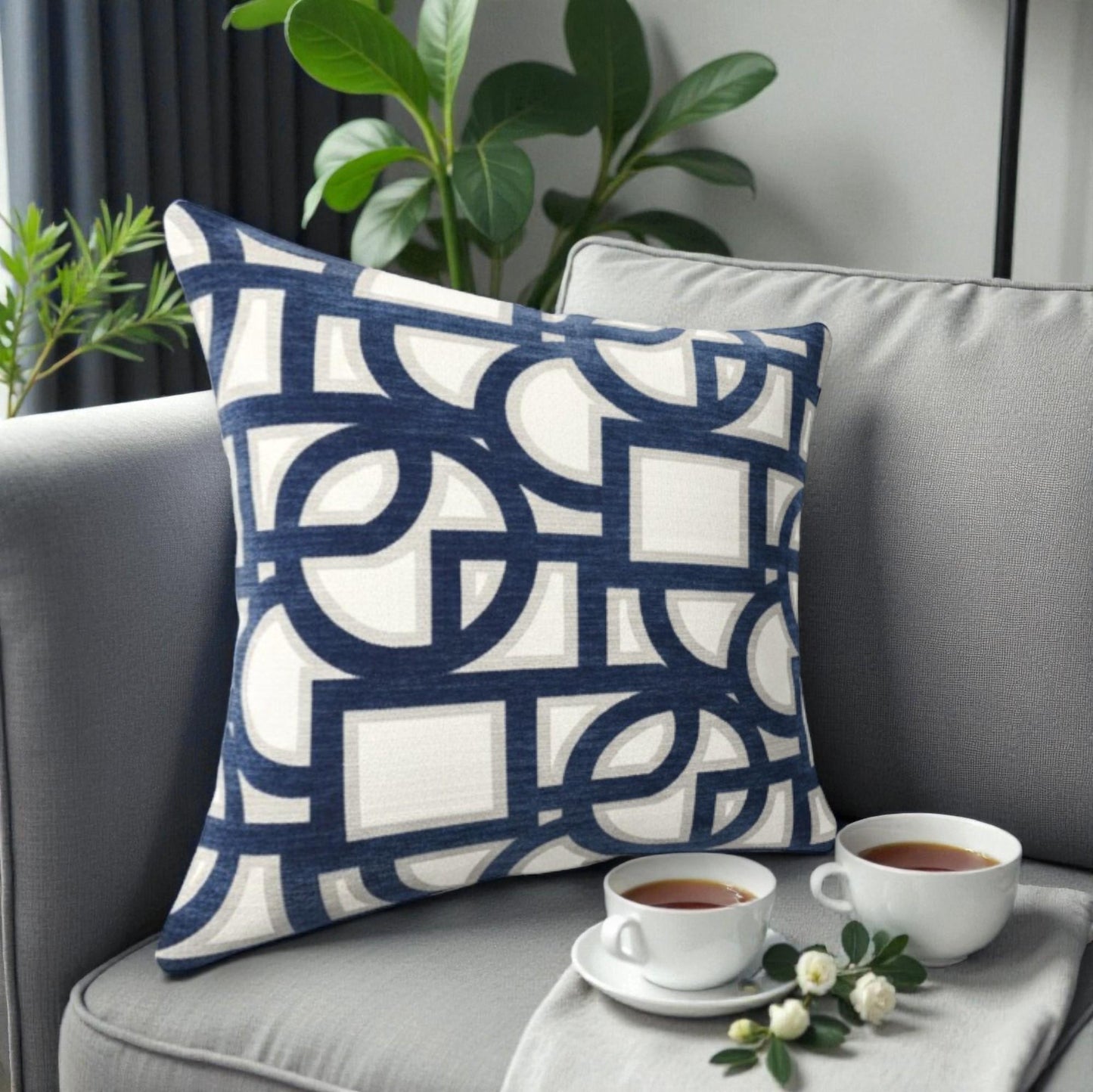 Decorative pillow with geometric pattern on a gray sofa with coffee cups and flowers.