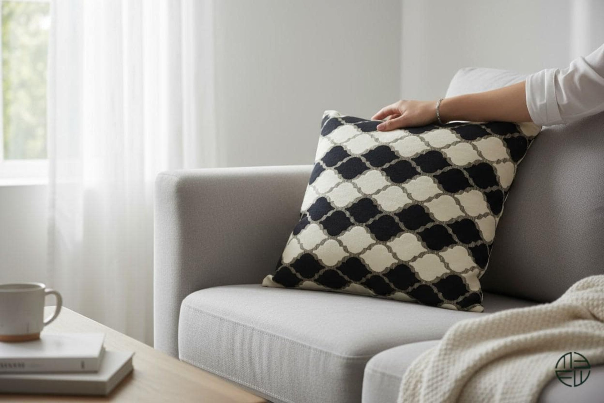 Black and white patterned pillow on a gray sofa in a bright living room.