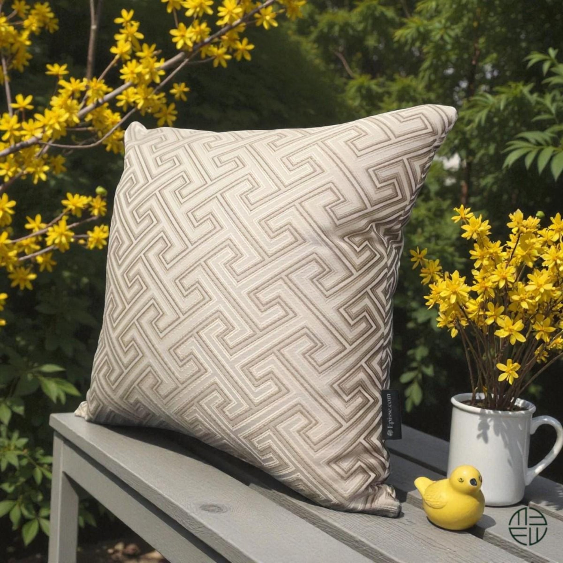 Boutique pillow with geometric pattern on a table outdoors with yellow flowers and a duck.