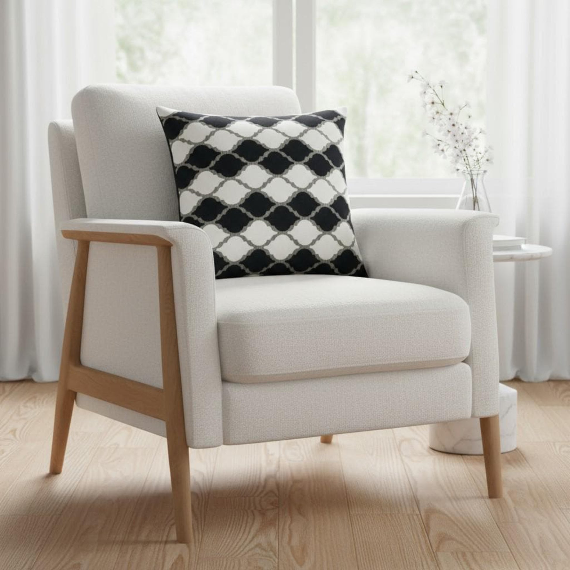 White armchair with a black and white patterned pillow in a bright room.