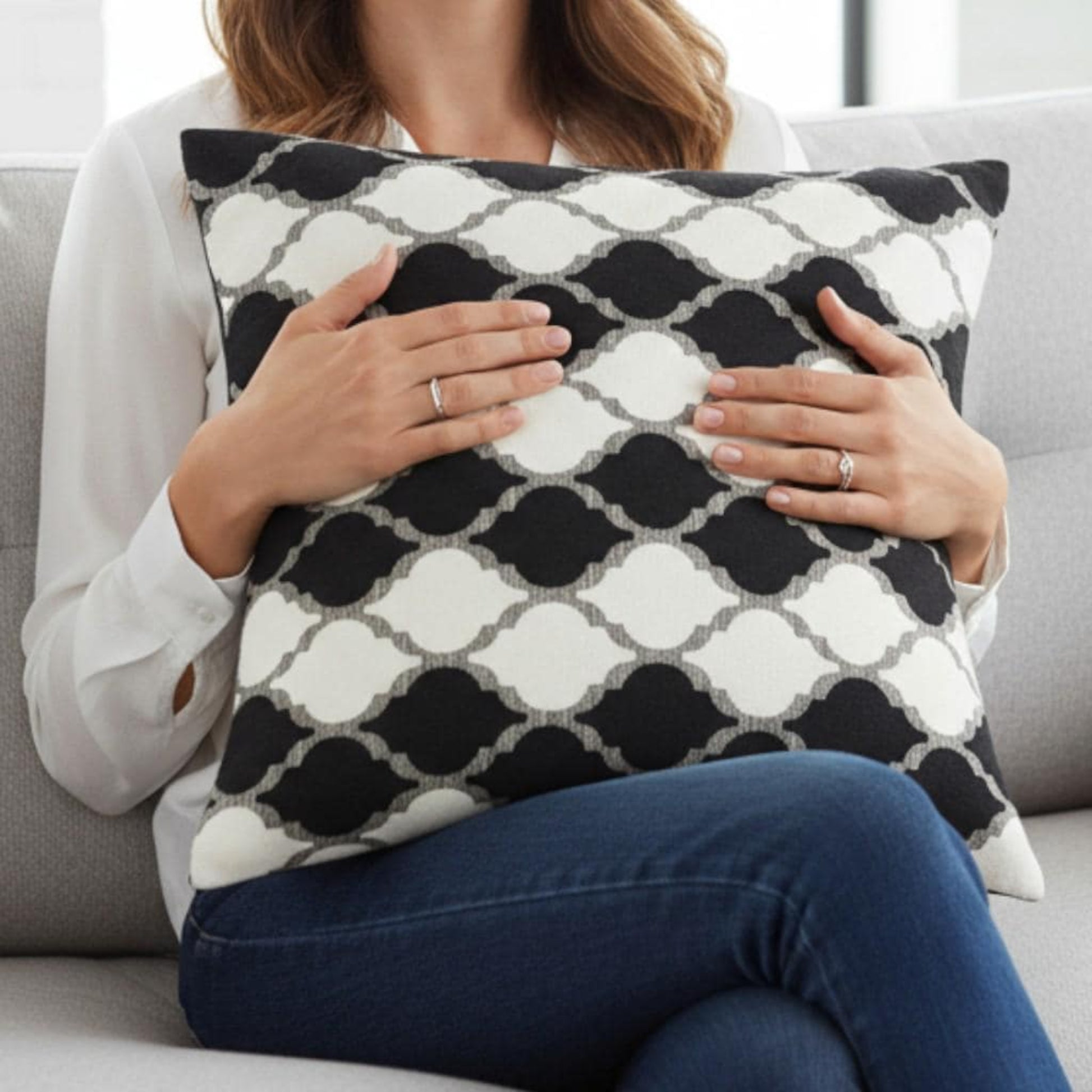 Person holding a black and white patterned pillow on a couch